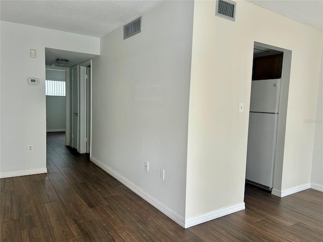 spare room with a textured ceiling, dark wood-style flooring, and visible vents