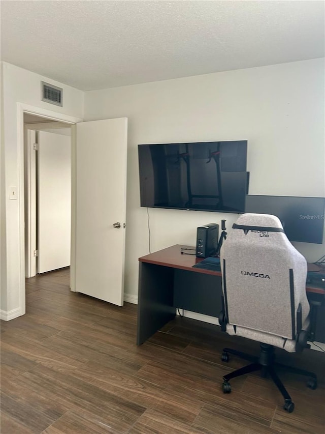 office area featuring visible vents, a textured ceiling, baseboards, and wood finished floors