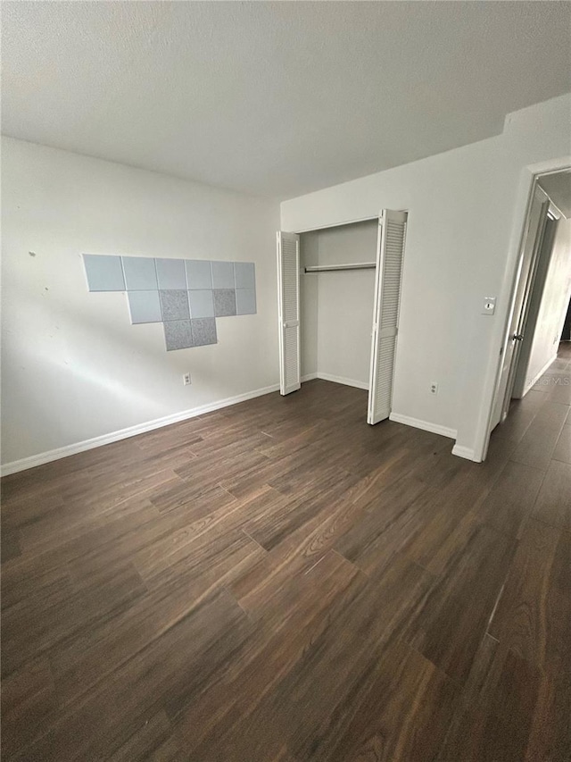 unfurnished bedroom with a closet, baseboards, dark wood finished floors, and a textured ceiling