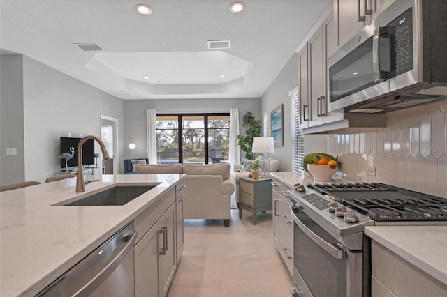 364 Palmaria Ct, Nokomis, FL 34275 - kitchen featuring stainless steel appliances, tasteful backsplash, a tray ceiling, light stone counters, and open floor plan