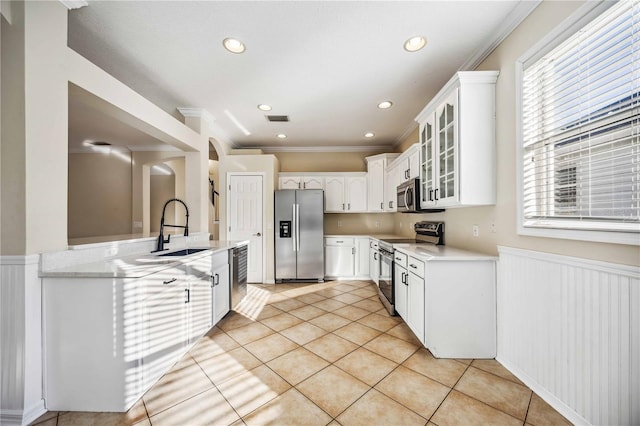 kitchen featuring sink, white cabinetry, stainless steel appliances, and ornamental molding