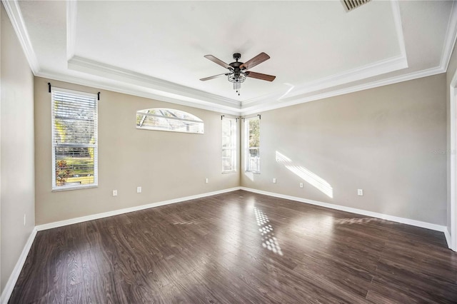 spare room with a raised ceiling, ceiling fan, dark wood-type flooring, and ornamental molding