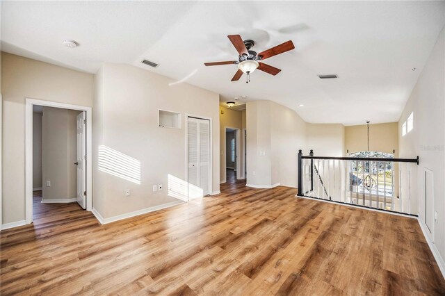 unfurnished room featuring hardwood / wood-style floors, ceiling fan with notable chandelier, and vaulted ceiling