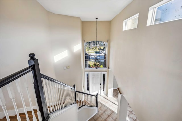 stairway featuring tile patterned floors, a chandelier, and a high ceiling