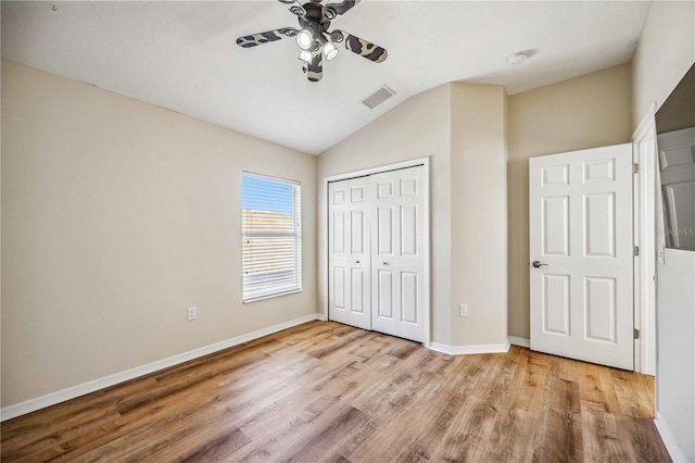 unfurnished bedroom featuring light wood-type flooring, a closet, vaulted ceiling, and ceiling fan