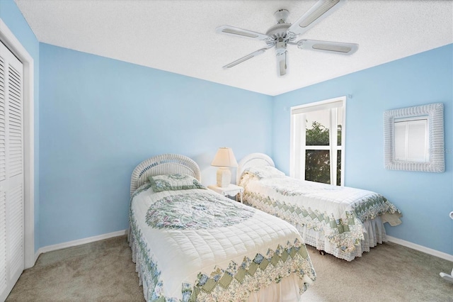 carpeted bedroom with ceiling fan, a closet, and a textured ceiling