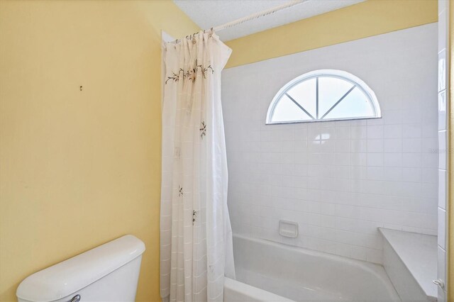 bathroom featuring toilet and shower / bath combo with shower curtain