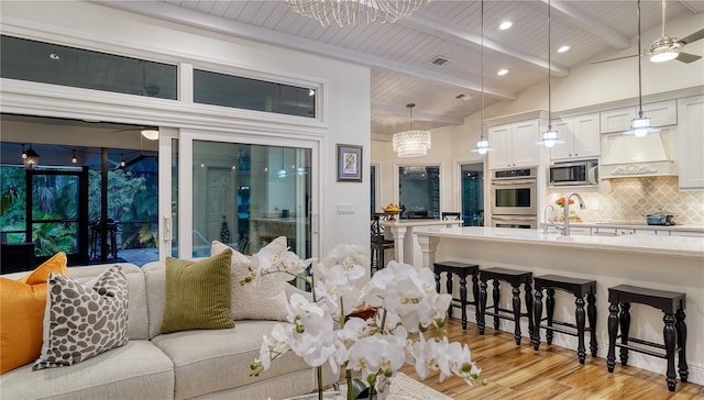 living room featuring sink, wooden ceiling, vaulted ceiling with beams, ceiling fan with notable chandelier, and light wood-type flooring