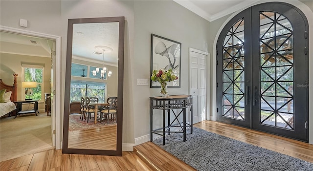 entrance foyer featuring a chandelier, french doors, hardwood / wood-style floors, and ornamental molding