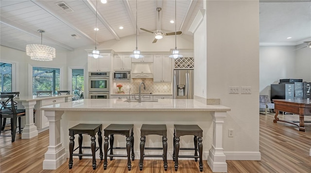 kitchen with hanging light fixtures, a kitchen breakfast bar, kitchen peninsula, ceiling fan with notable chandelier, and appliances with stainless steel finishes