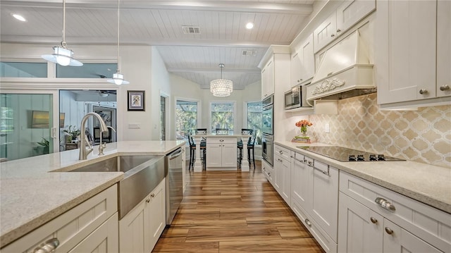 kitchen with beam ceiling, stainless steel appliances, hanging light fixtures, and custom exhaust hood