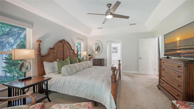 carpeted bedroom with a tray ceiling and ceiling fan