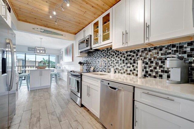 kitchen featuring white cabinets, sink, light hardwood / wood-style flooring, light stone countertops, and stainless steel appliances