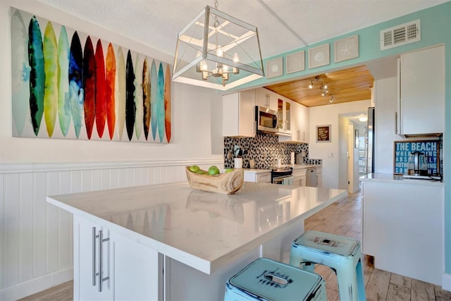 kitchen featuring white cabinets, pendant lighting, and light hardwood / wood-style floors