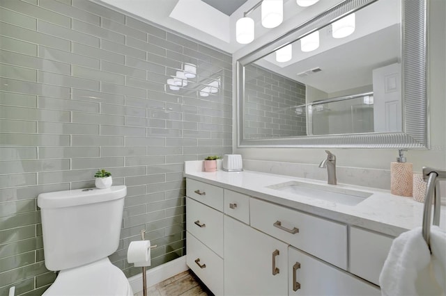 bathroom with a shower with door, vanity, and toilet