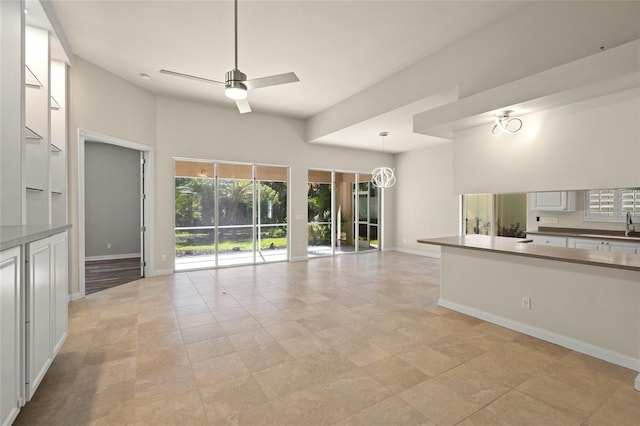 unfurnished living room featuring light tile patterned floors, ceiling fan with notable chandelier, and sink