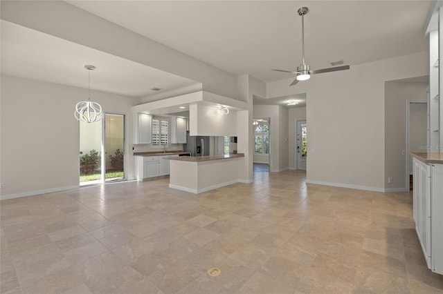 kitchen featuring white cabinetry, stainless steel refrigerator with ice dispenser, ceiling fan with notable chandelier, decorative light fixtures, and kitchen peninsula