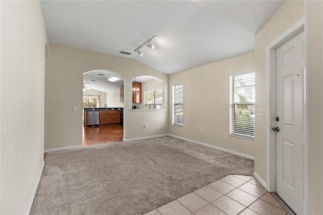 unfurnished room featuring lofted ceiling, light carpet, track lighting, sink, and ceiling fan