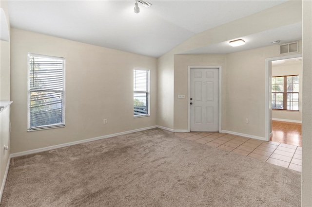 tiled empty room with a wealth of natural light and lofted ceiling