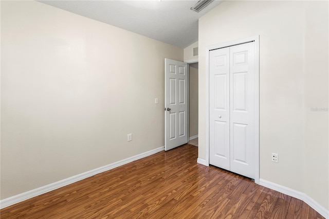 unfurnished bedroom featuring a closet, dark wood-type flooring, and lofted ceiling