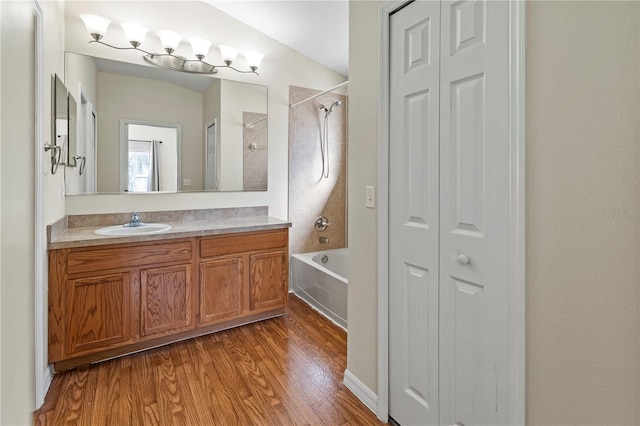 bathroom with vanity, hardwood / wood-style flooring, vaulted ceiling, and tiled shower / bath combo