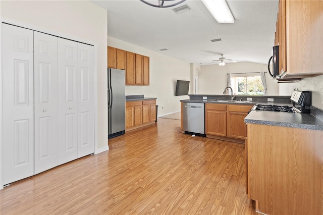 kitchen with ceiling fan, sink, stainless steel appliances, and light wood-type flooring