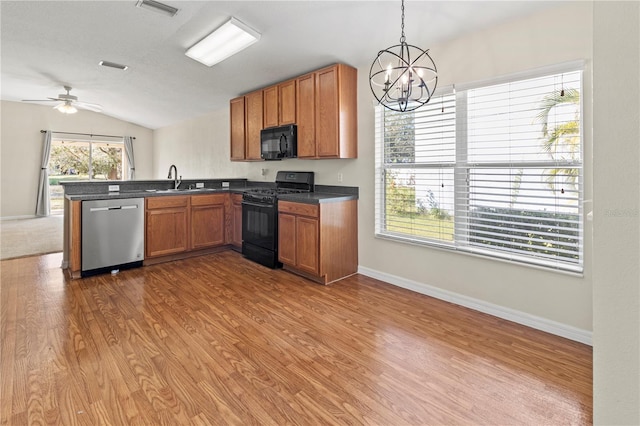 kitchen with kitchen peninsula, ceiling fan with notable chandelier, black appliances, pendant lighting, and lofted ceiling