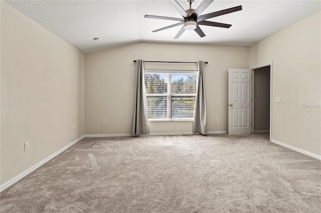 carpeted empty room featuring ceiling fan, lofted ceiling, and a textured ceiling