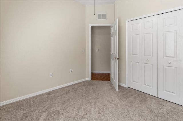 unfurnished bedroom with light colored carpet and a closet