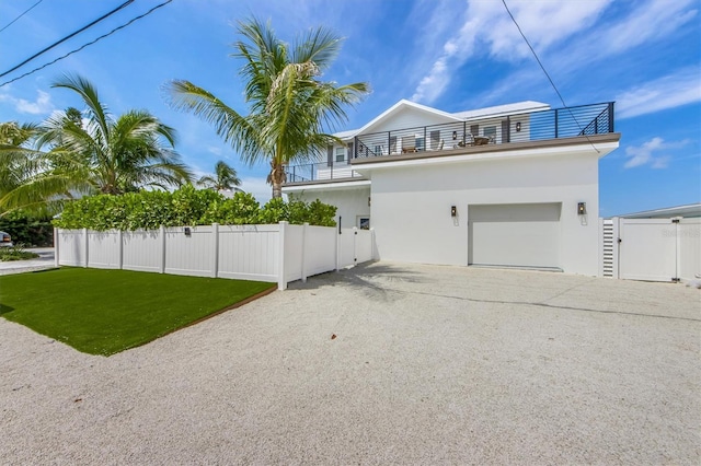 view of side of home featuring a balcony, a garage, and a lawn