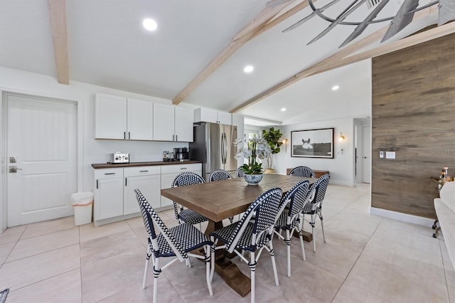 tiled dining space with lofted ceiling with beams and wood walls