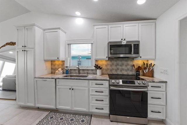 kitchen featuring sink, white cabinetry, stainless steel appliances, and vaulted ceiling