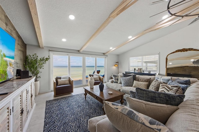 living room featuring vaulted ceiling with beams, light hardwood / wood-style flooring, a water view, and a textured ceiling