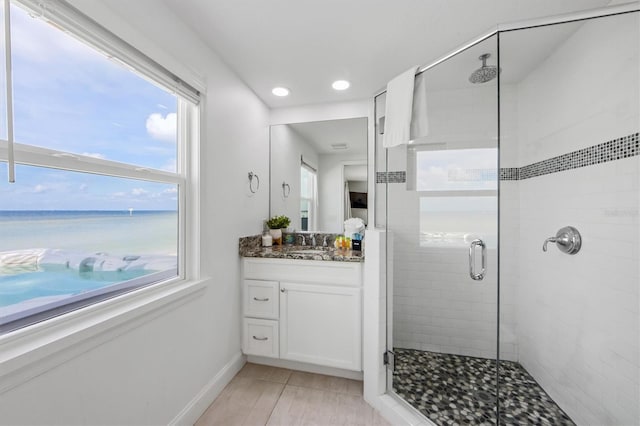 bathroom with an enclosed shower, vanity, a water view, and tile patterned floors