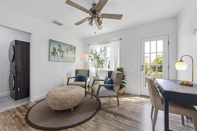 sitting room featuring ceiling fan, wood-type flooring, and stacked washer and dryer