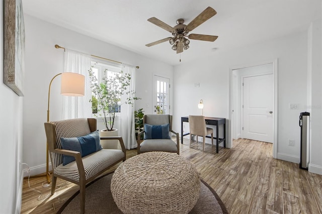 sitting room with ceiling fan and wood-type flooring