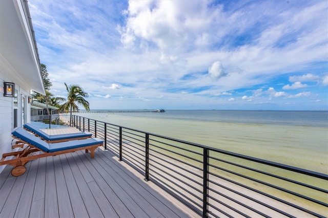 wooden terrace featuring a water view and a view of the beach