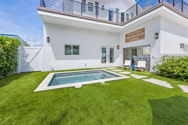 rear view of property with a lawn, french doors, and a balcony