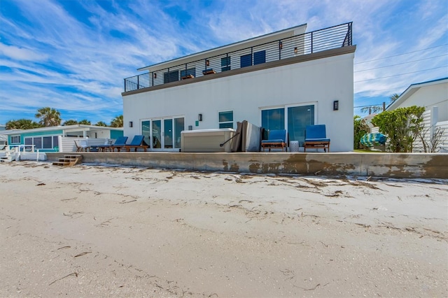 back of property featuring a patio, a balcony, and a hot tub