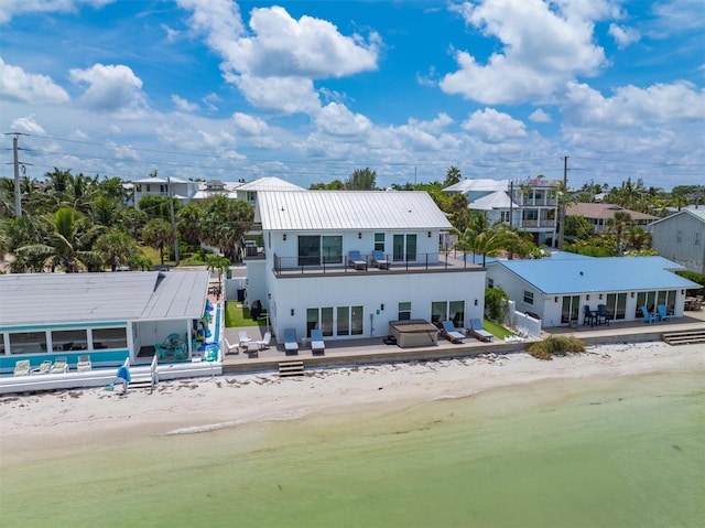 back of house featuring a patio area, a view of the beach, and a jacuzzi