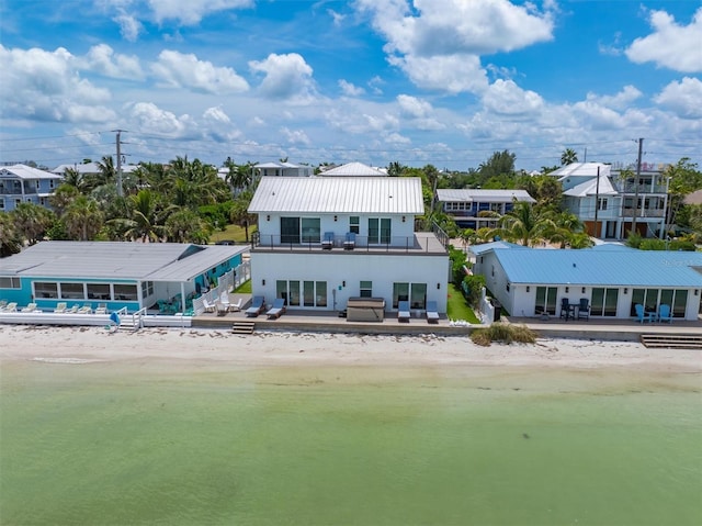 rear view of property featuring a water view, a patio, and a view of the beach