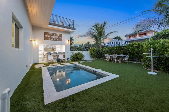 pool at dusk featuring a lawn