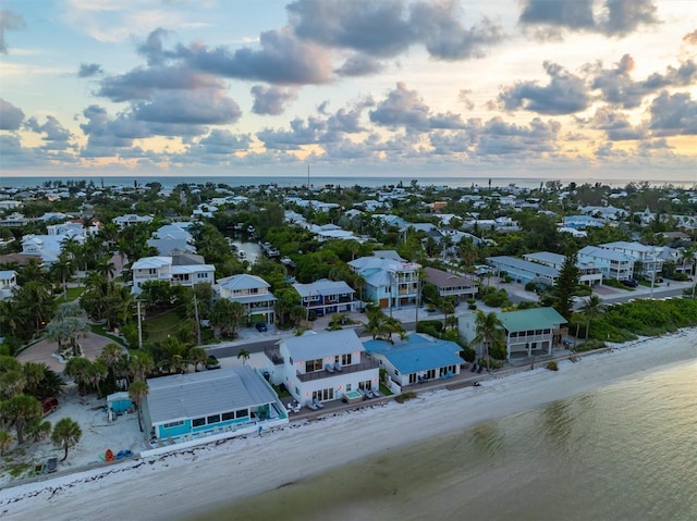 aerial view at dusk with a water view and a beach view