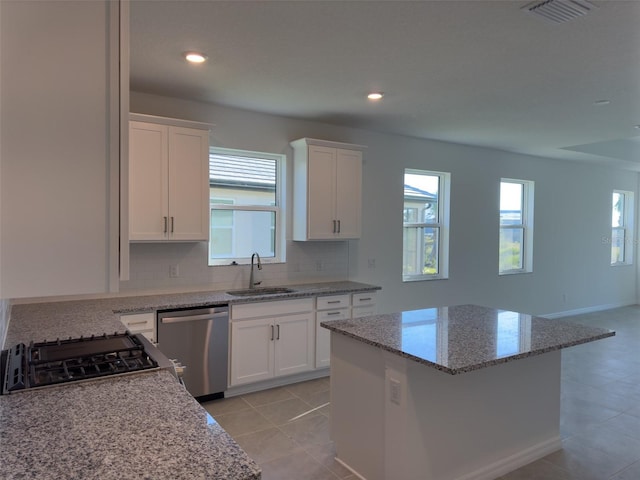 kitchen featuring dishwasher, white cabinetry, a kitchen island, and sink