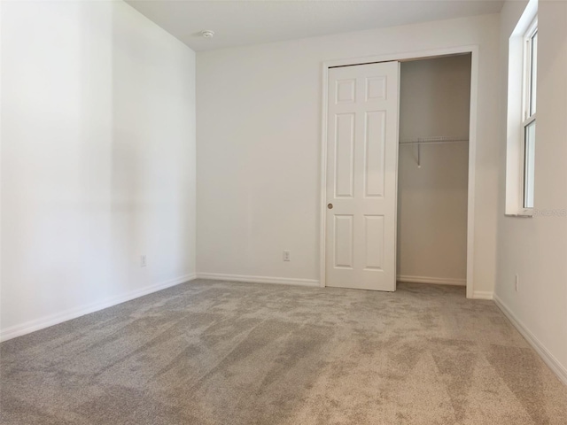 unfurnished bedroom with a closet and light colored carpet