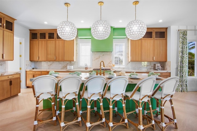 kitchen with a kitchen island with sink, pendant lighting, decorative backsplash, and light parquet flooring