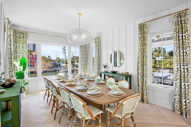 dining space featuring light parquet floors, plenty of natural light, a water view, and an inviting chandelier