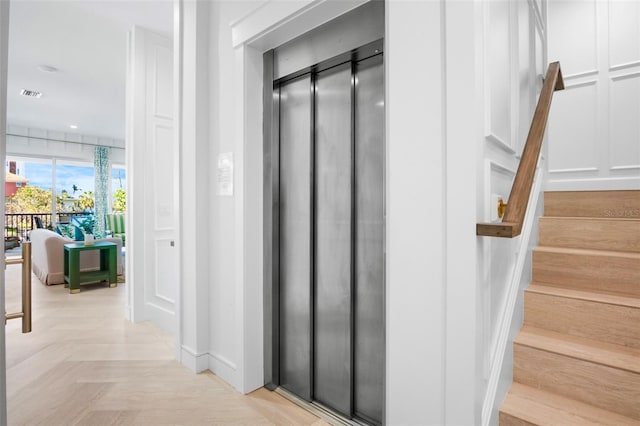 stairway featuring elevator and parquet flooring