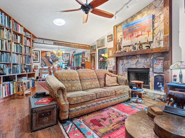 living room featuring hardwood / wood-style floors, a textured ceiling, vaulted ceiling, and a stone fireplace