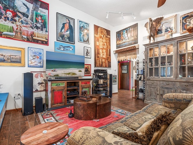 living room featuring a textured ceiling, ceiling fan, and dark wood-type flooring